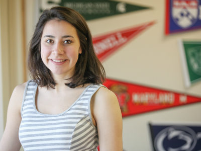 teen girl smiling in front of college pennants